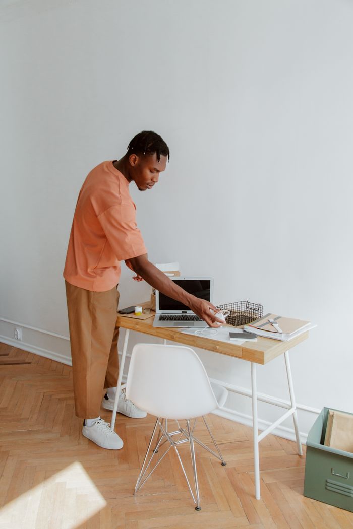 about-us-01 A man standing at a desk organizing papers and electronic devices in a modern office setting.